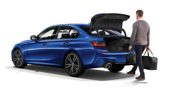 BMW Серија 3 Седан, автоматско отворање на багажникот. Тричетвртински заден кадар на BMW Серија 3 Седан во мирување и возач што автоматски го отвора багажникот со стапалото.