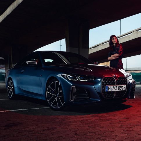 Model standing next to BMW M440i xDrive Coupé G22 2020 three quarter side view BMW M440i xDrive Coupé Arctic Race Blue metallic G22 2020 three quarter side view with model