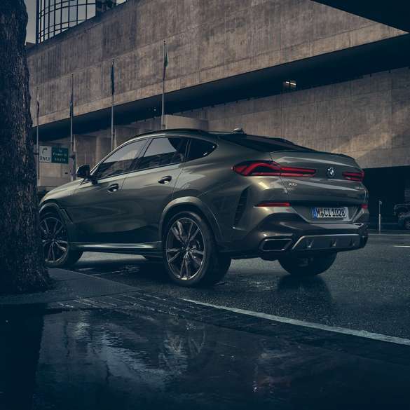 BMW X6 надворешност. BMW X6 од тричетвртинска перспектива одзади пред урбана заднина.