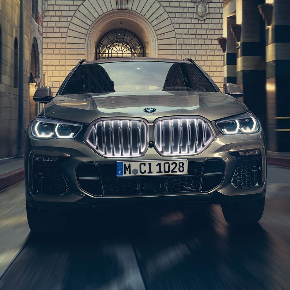 BMW X6 со BMW ‘Iconic Glow’ бубрежна решетка. BMW X6 поглед однапред пред урбана заднина.