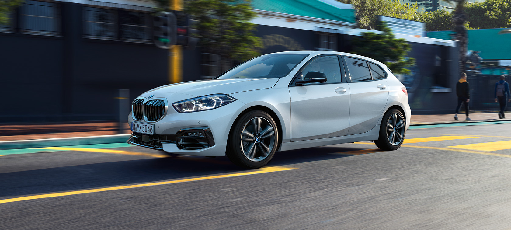 BMW Серија 1, модел Sport Line, тричетвртински страничен приказ BMW Серија 1, модел Sport Line во Mineral White бела металик боја, тричетвртински страничен приказ во возење.