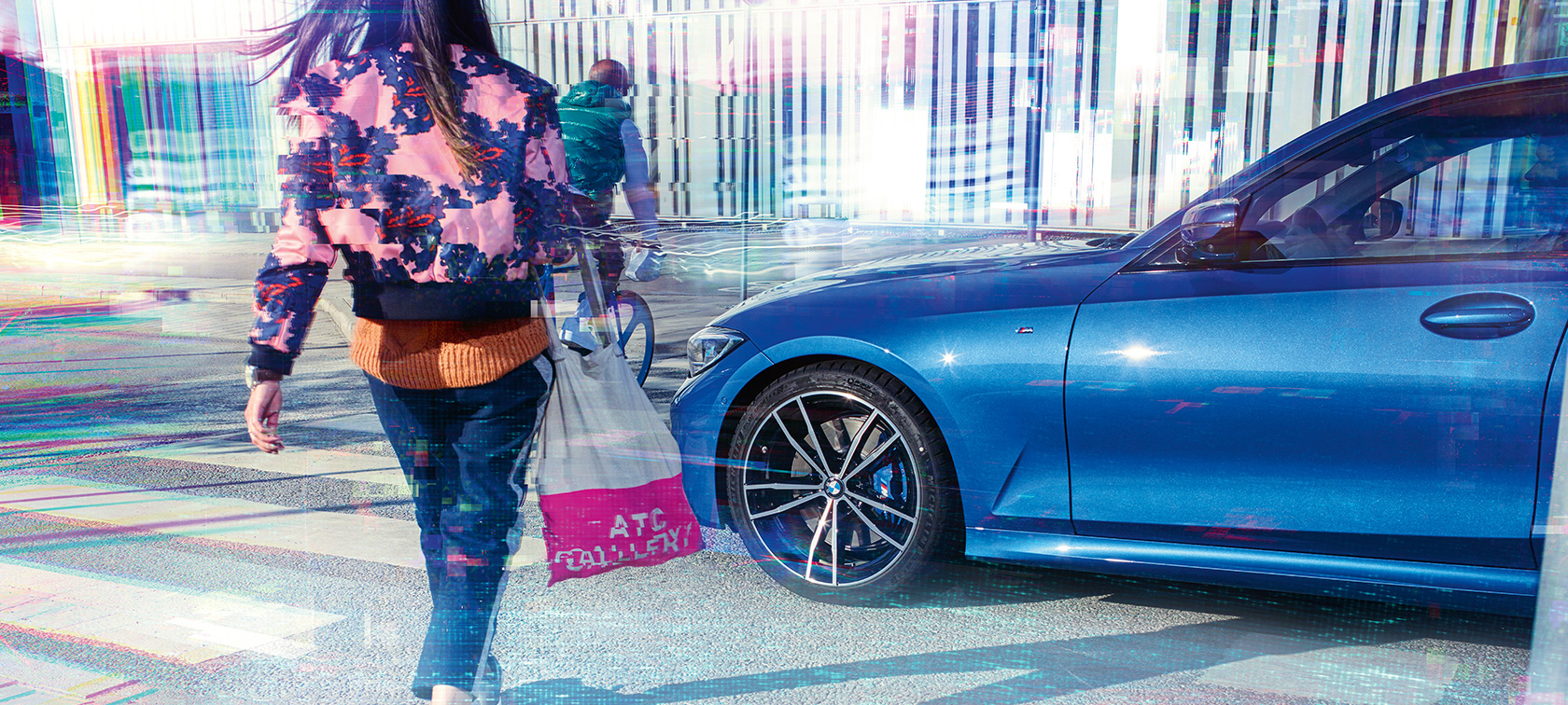 BMW Серија 3 Седан, тричетвртински страничен кадар. Тричетвртински страничен поглед на BMW Серија 3 Седан на асфалт пред урбана заднина со патници.