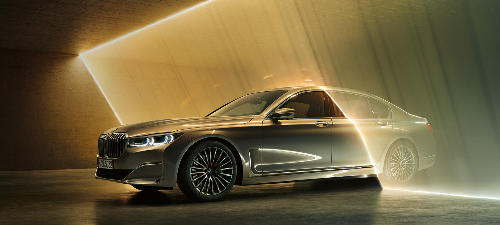 BMW Серија 7 Седан во тричетвртински преден кадар BMW Серија 7 Седан: сив BMW во тричетвртински преден кадар опкружен со снопови светлина