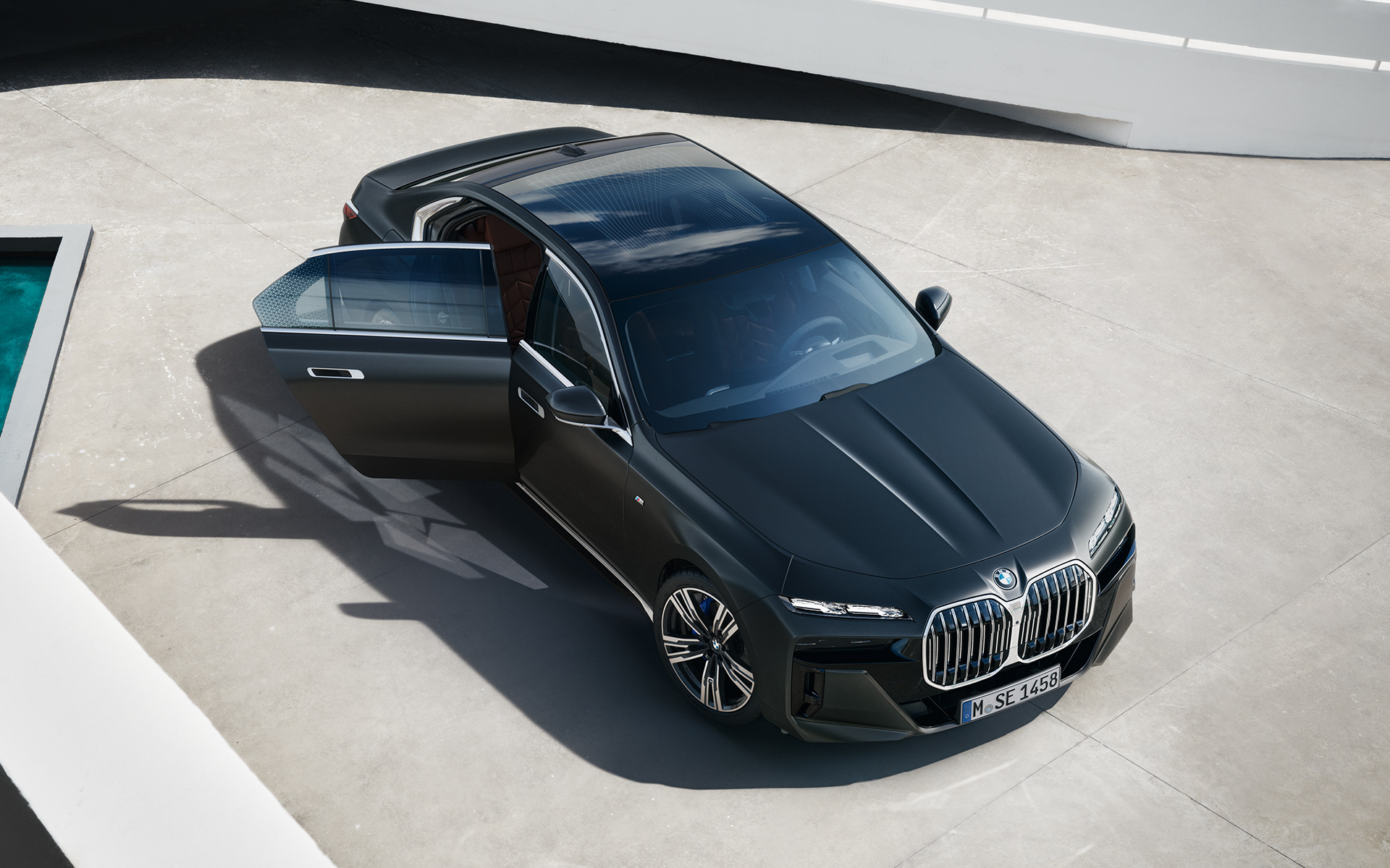 Поглед одозгора на BMW Серија 7 Седан G70 ICE 740i M спорт пакет Frozen Deep Grey сива металик боја BMW Серија 7 Седан G70 ICE 740i M спорт пакет Frozen Deep Grey сива металик боја поглед одозгора со отворена врата на совозачот