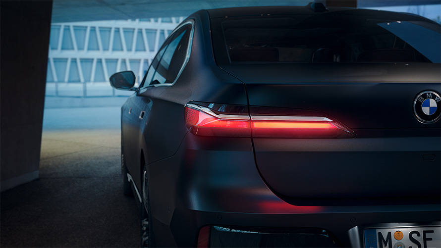 BMW Серија 7 Седан G70 ICE 740i M спорт пакет Frozen Deep Grey сива металик боја поглед одзади со црвено сјајно задно светло во тунел