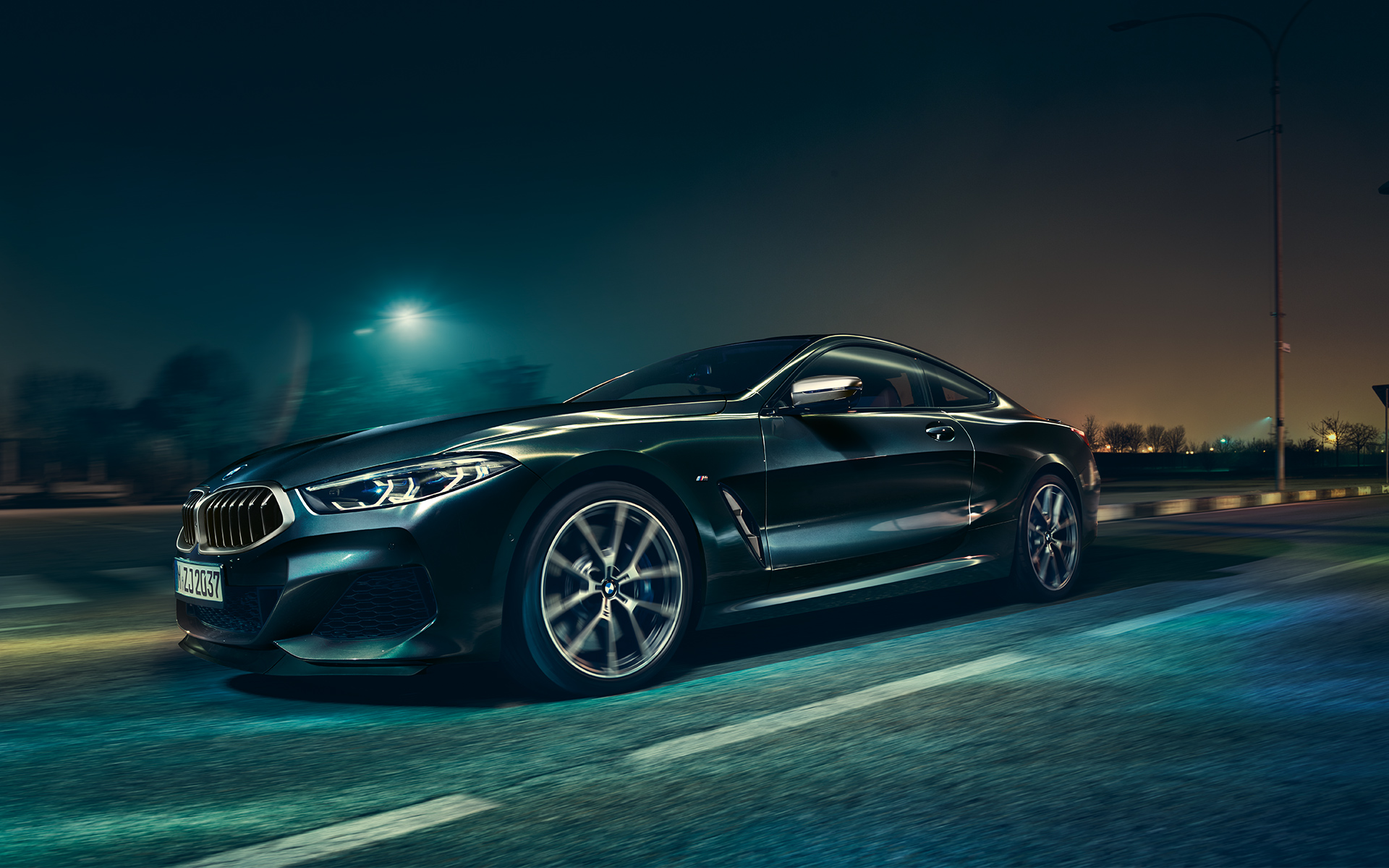 Тричетвртински преден замрзнат кадар на BMW Серија 8 Coupé во урбана средина ноќе.