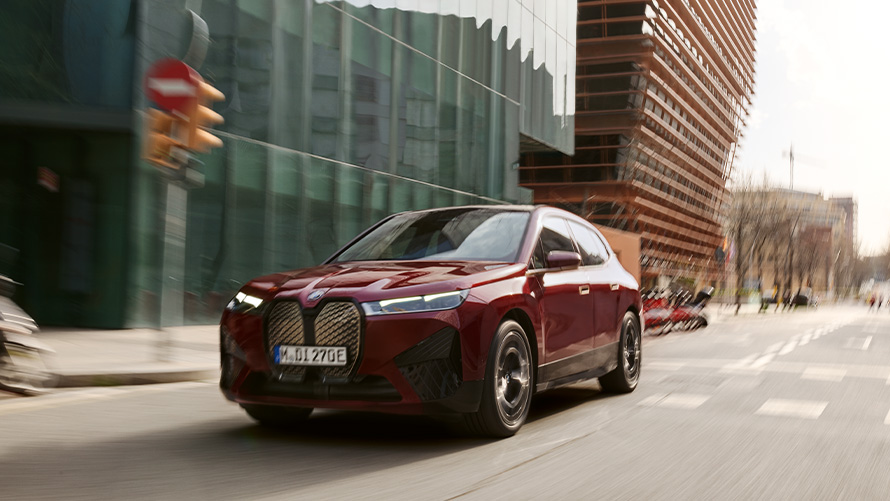 BMW iX i20 електричен SUV BMW iX xDrive50 помош при возење BMW iX i20 2021 електричен SUV BMW iX xDrive50 Aventurin Red црвена боја вози во урбана средина