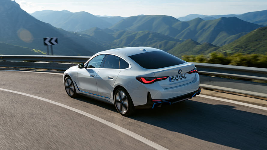 Тричетвртински поглед одзади на BMW i4 eDrive40 G26 2021 во возење BMW i4 eDrive40 G26 2021 Mineral White тричетвртински поглед одзади во возење