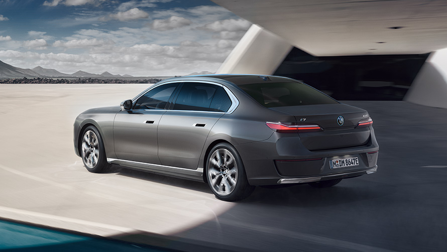 BMW i7 Седан пакет 3/4 поглед одзади BMW i7 Седан G70 BMW Individual Oxid grey сива металик боја 3/4 поглед одзади паркиран пред зграда