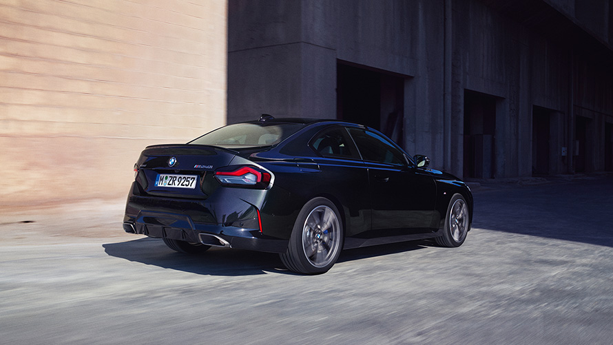 BMW M240i xDrive Coupé G42 2021 Black Sapphire металик тричетвртински поглед одзади паркиран пред магацин