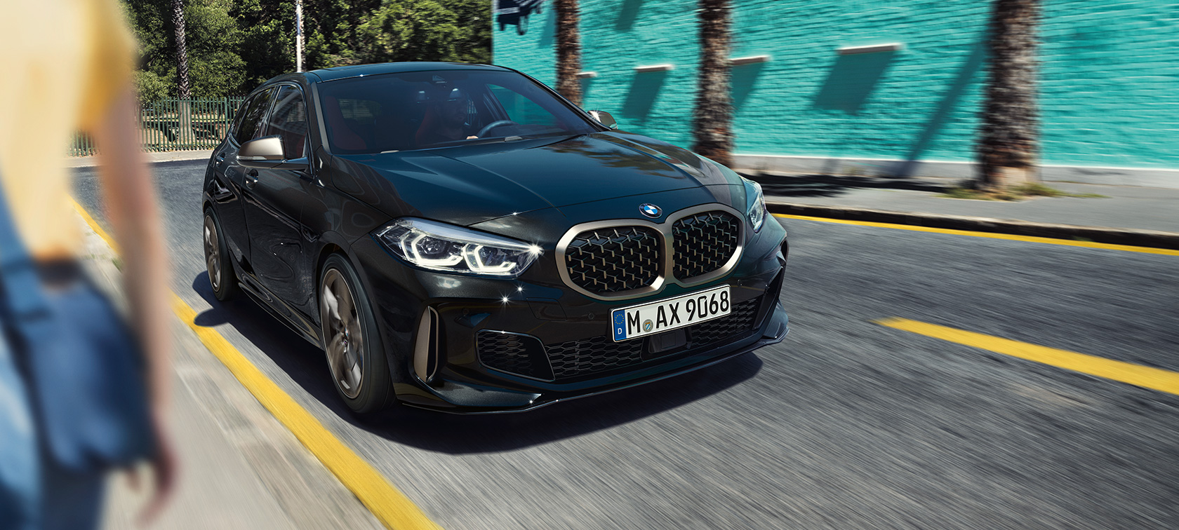 BMW M135i xDrive, тричетвртински приказ однапред. BMW M135i xDrive во Black Sapphire црна металик боја, тричетвртински приказ однапред во возење.