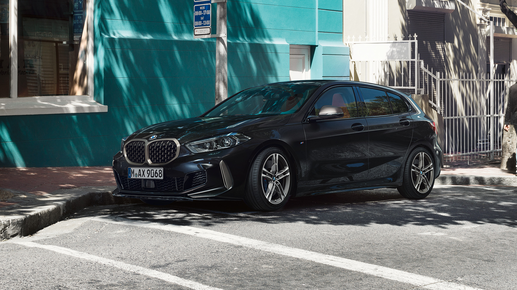 BMW M135i xDrive, тричетвртински страничен приказ. Потполно новиот BMW M135i xDrive во Black Sapphire црна металик боја, тричетвртински страничен приказ додека стои во место.