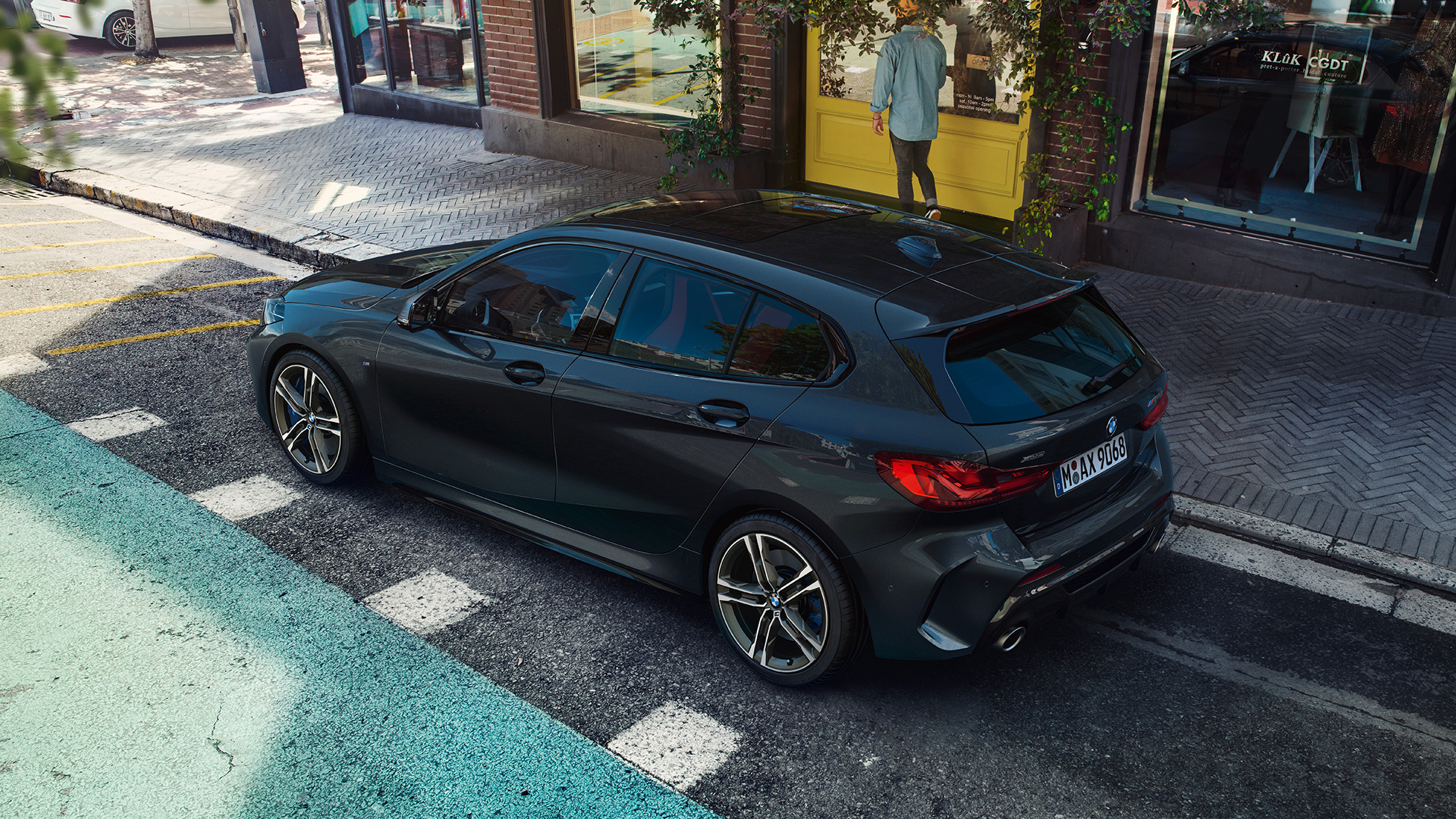 BMW M135i xDrive, парикиран. BMW M135i xDrive во Black Sapphire црна металик боја, паркиран, страничен приказ од птичја перспектива.