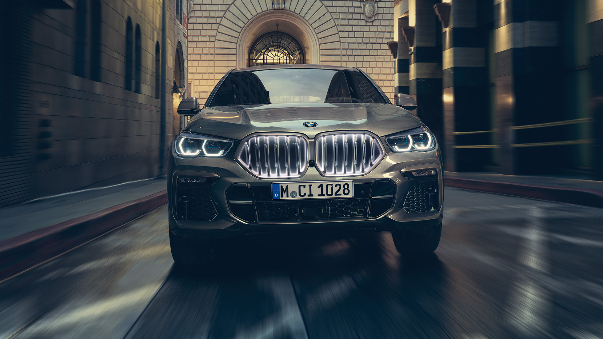 BMW X6 M50i со BMW бубрежна решетка „Iconic Glow” BMW X6 M50i приказ однапред пред урбана заднина.