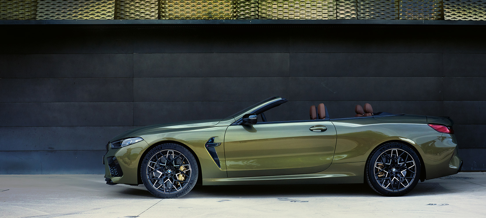 BMW M8 Competition кабриолет F91 LCI Facelift 2022 поглед отстрана на паркинг BMW M8 Competition кабриолет F91 LCI Facelift 2022 BMW Individual Brass металик боја, поглед отстрана на паркинг, со отворена врата и женски модел