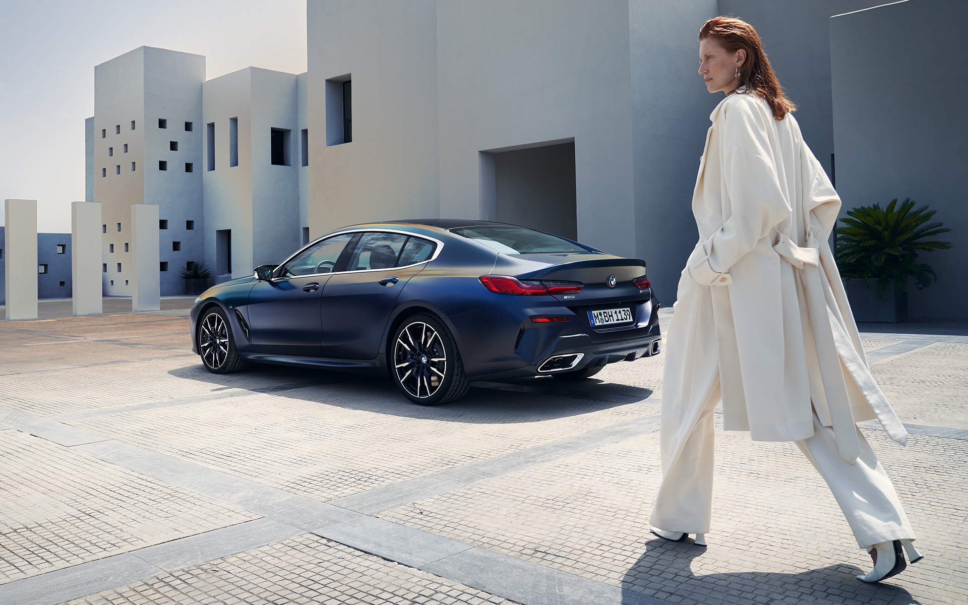 BMW M850i xDrive Gran Coupé G16 LCI Facelift 2022 страничен поглед со женски модел BMW M850i xDrive Gran Coupé G16 LCI Facelift 2022 BMW Individual Frozen Tanzanite Blue металик тричетвртински поглед одназад до женски модел