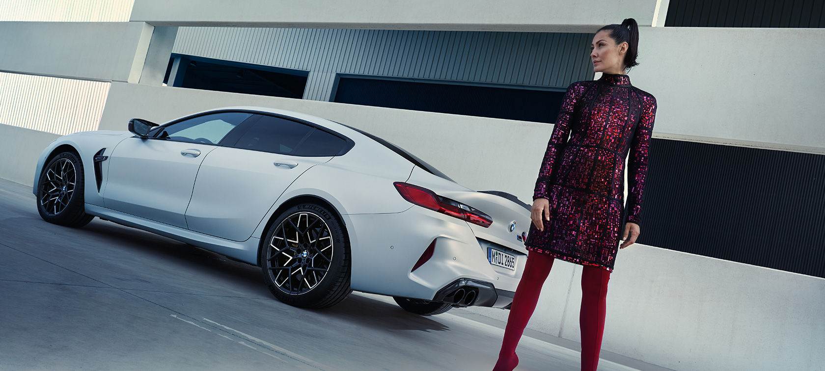 Тричетвртински поглед одназад BMW M8 Competition Gran Coupé F93 LCI 2022 BMW M8 Competition Gran Coupé F93 LCI Facelift 2022 BMW Individual Frozen Brilliant White металик боја, тричетвртински поглед одназад со женски модел кој стои до возилото
