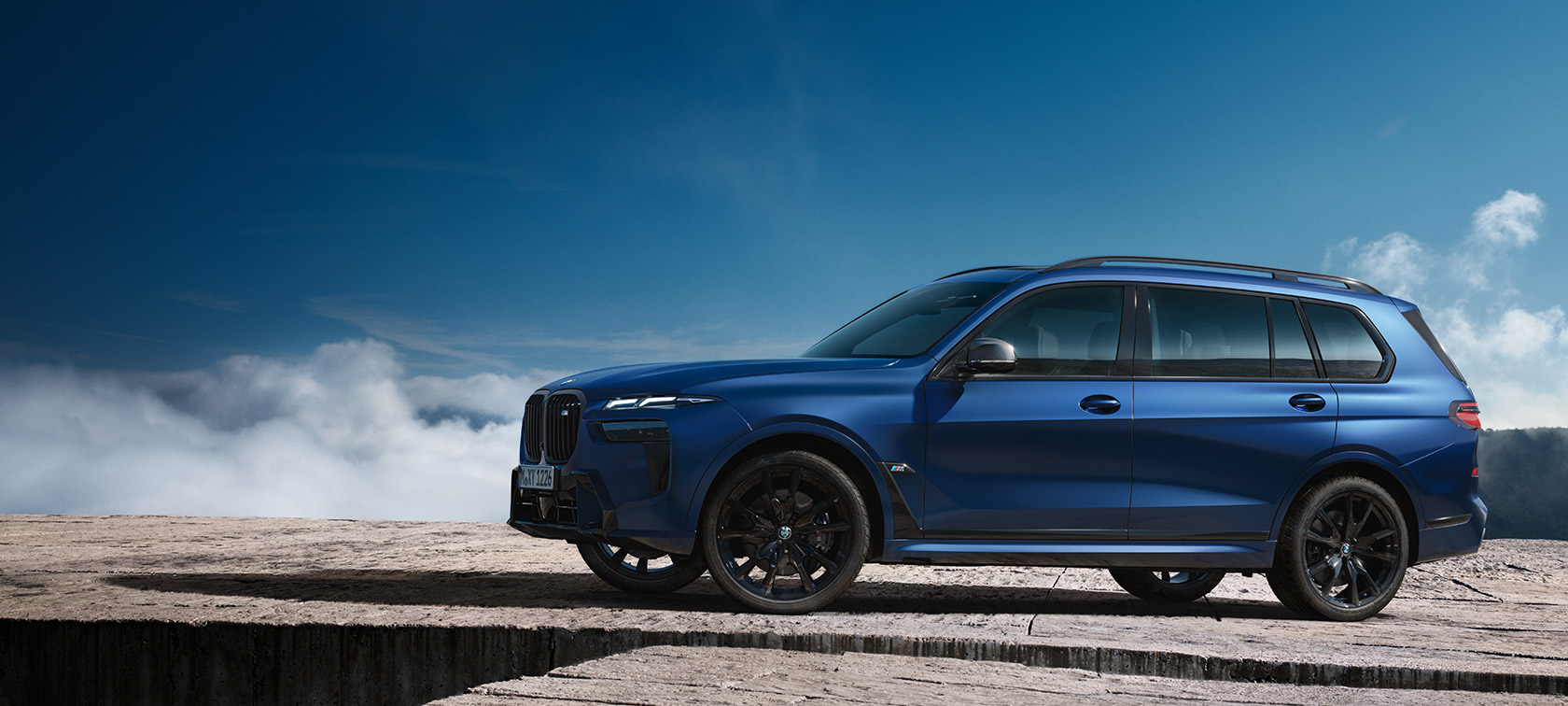 BWM X7 M60i xDrive G07 LCI Frozen Marina Bay Blue поглед отстрана пред планински пејзаж