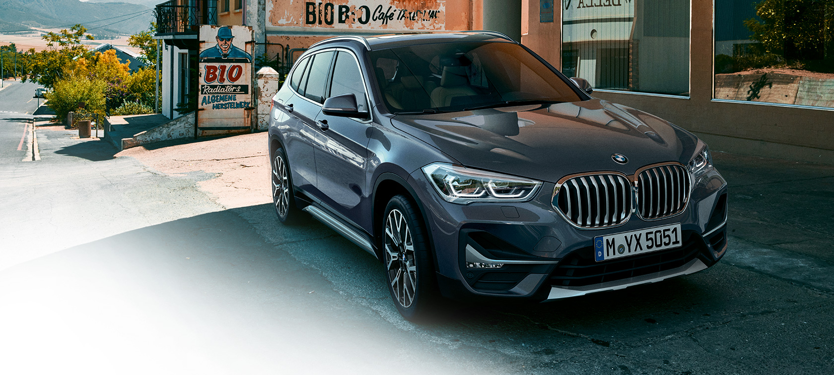 BMW X1, тричетвртински приказ однапред. BMW X1, тричетвртински приказ однапред пред урбана заднина.