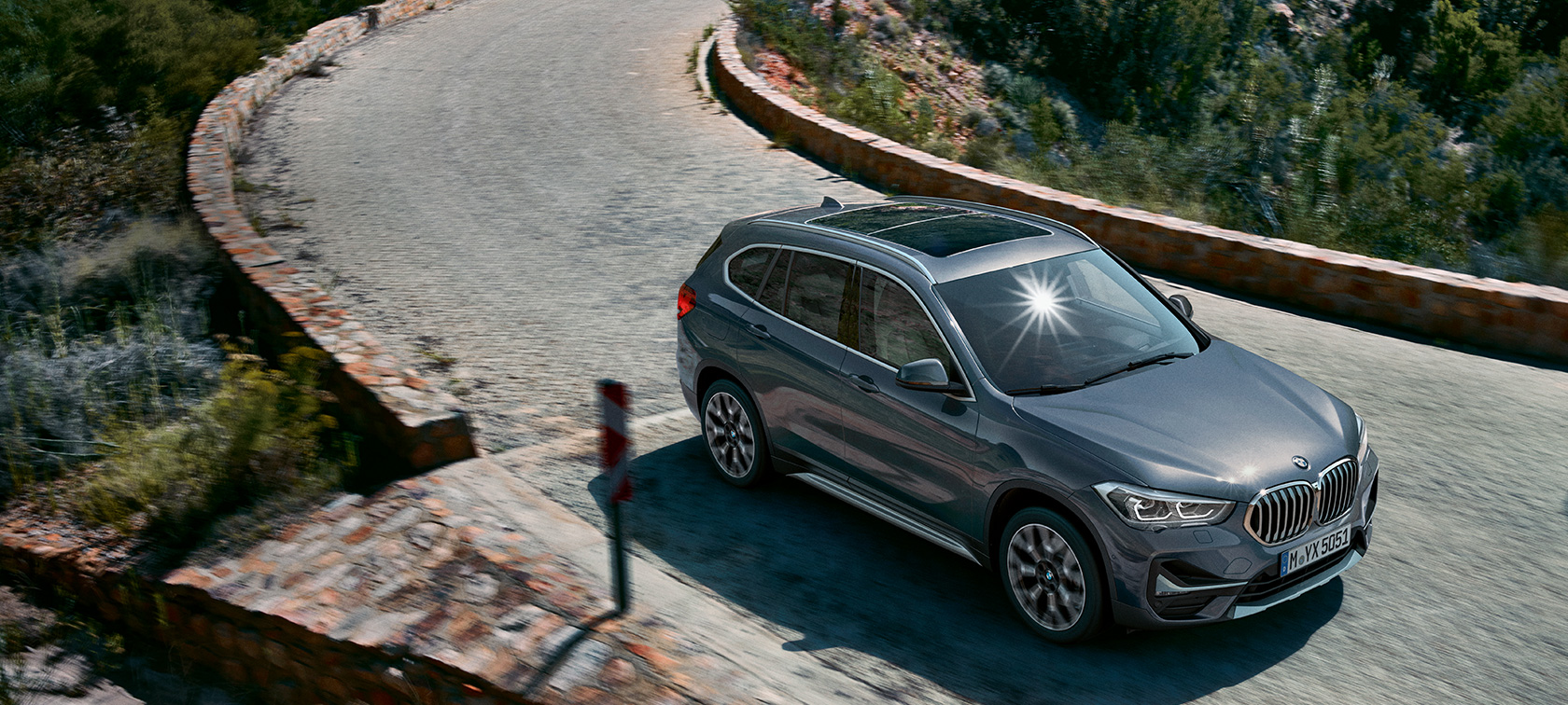 BMW X1, тричетвртински приказ однапред BMW X1, тричетвртински приказ однапред при возење низ планински пејсаж.