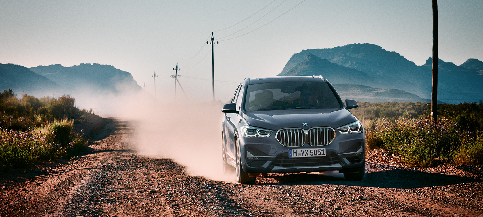 BMW X1, тричетвртински приказ одзади BMW X1, тричетвртински приказ одзади при возење среде планински пејзаж.
