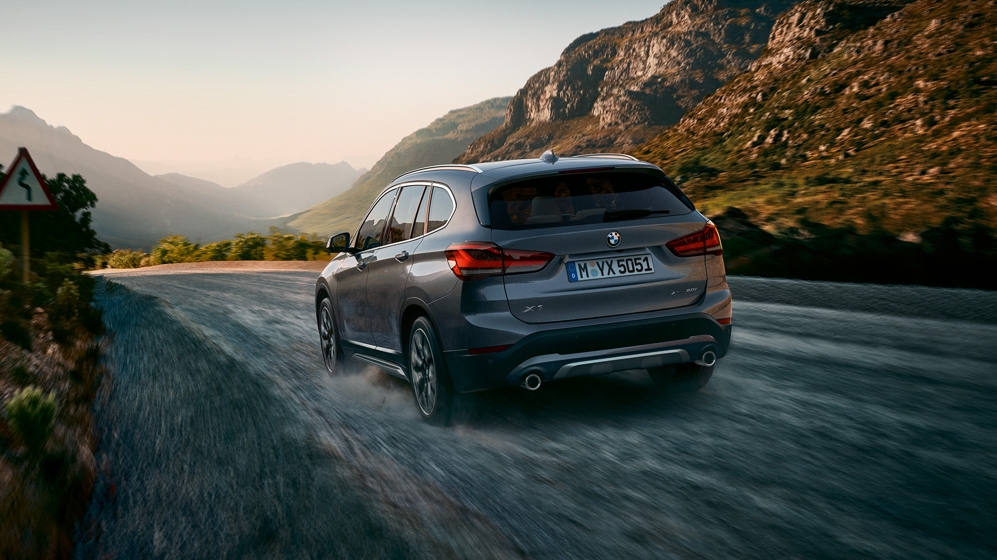 BMW X1, тричетвртински приказ одзади. BMW X1, тричетвртински приказ одзади при возење сред планински пејзаж.
