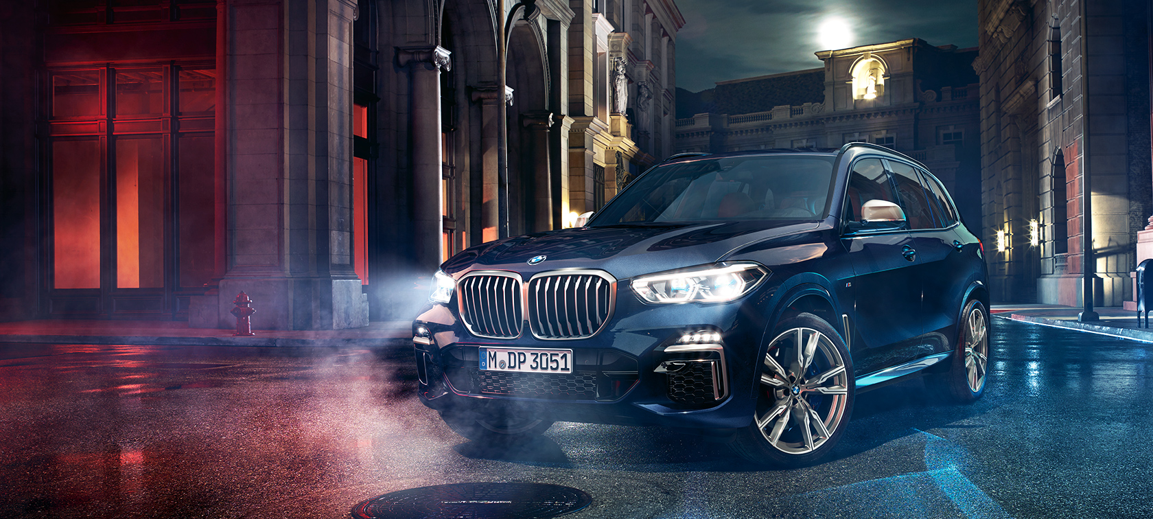 BMW X5 M50d на пат BMW X5 M50d стои на пат ноќе со градот во заднина