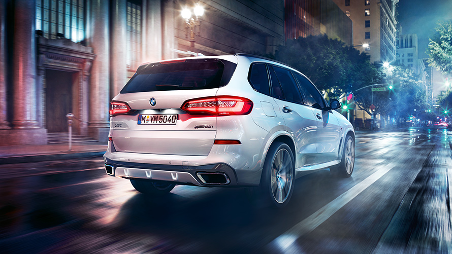 Кадар на задниот дел на BMW X5 M50d со урбана заднина ноќе 