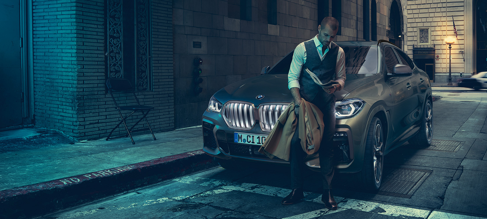 Маж потпрен на BMW X6. Маж потпрен на BMW X6, страничен приказ пред урбана заднина.