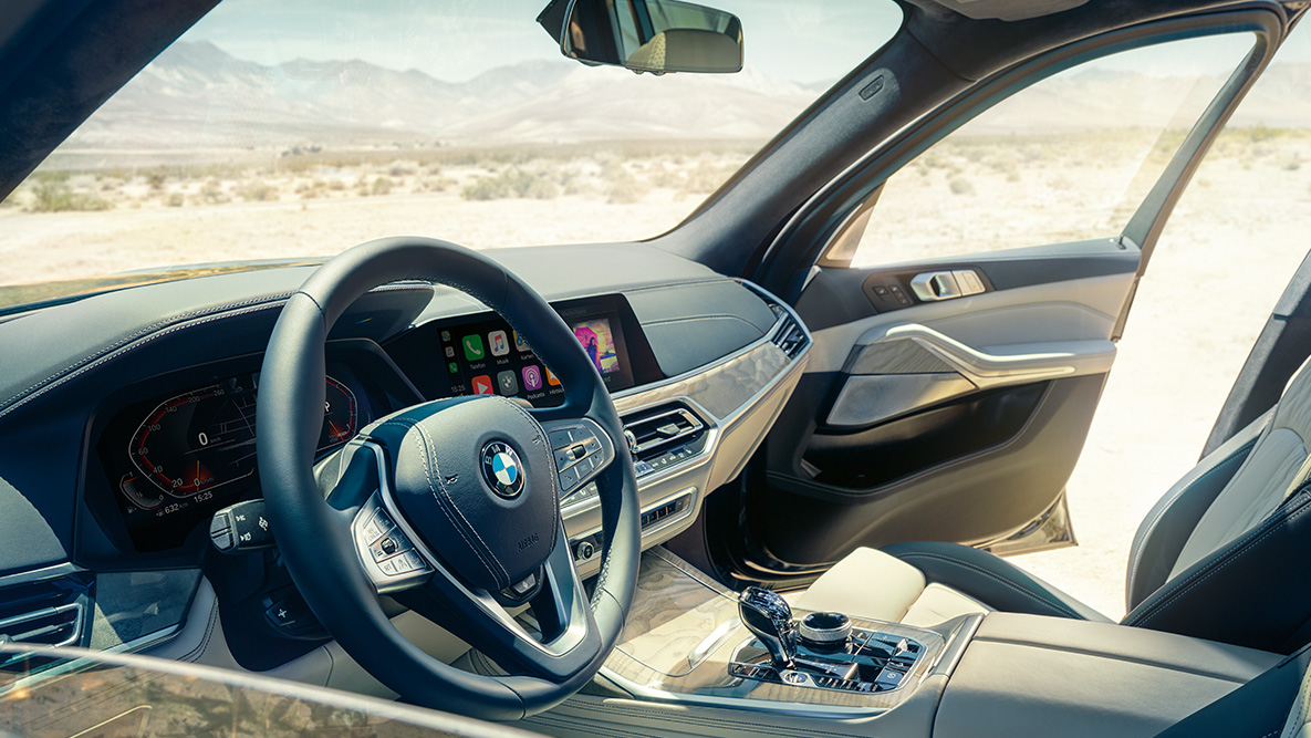 Внатрешност на BMW X7 Внатрешност на BMW X7: поглед однадвор кон предниот ред седишта со поглед кон воланот, интрумент таблата и кожните седишта