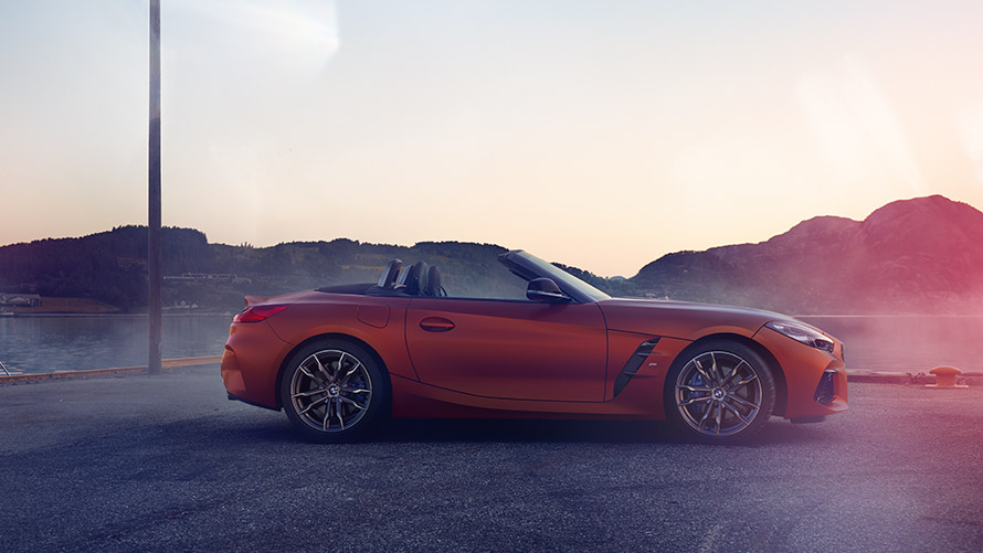 Портокалов BMW Z4 First Edition стои во кривина Портокалов BMW Z4 First Edition стои во кривина пред планински пејзаж