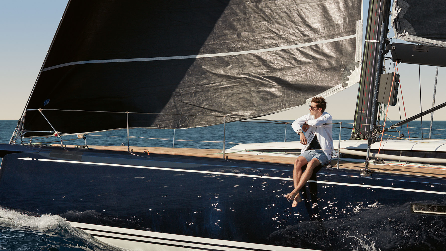 A man is shown sitting on a yacht wearing a BMW Yachtsport Men’s Jacket from the BMW Yachtsport Collection. A man is shown sitting on a yacht wearing a BMW Yachtsport Men’s Jacket from the BMW Yachtsport Collection.