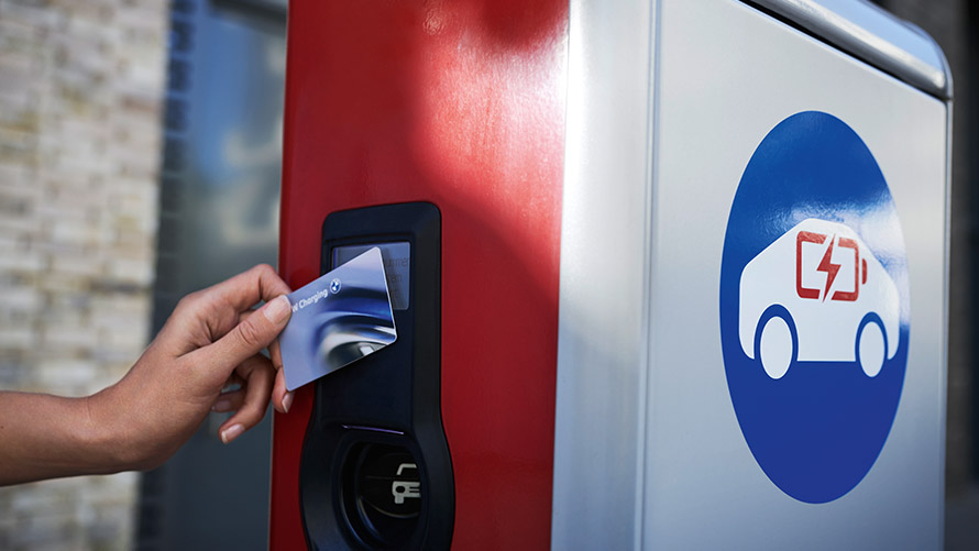 Маж држи BMW Charging Card на јавна станица за полнење